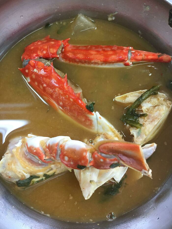 Crab soup served as a unique school lunch from around the world in a metal bowl with herbs.