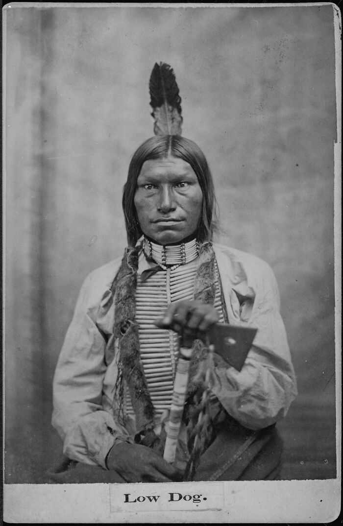 Historical photo of Low Dog in traditional attire, holding an object, showcasing important moments in history.