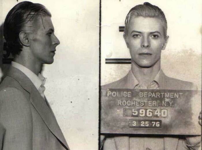 Historic photo of an unidentified person in a mugshot, wearing a suit, taken in Rochester, NY, 1976.