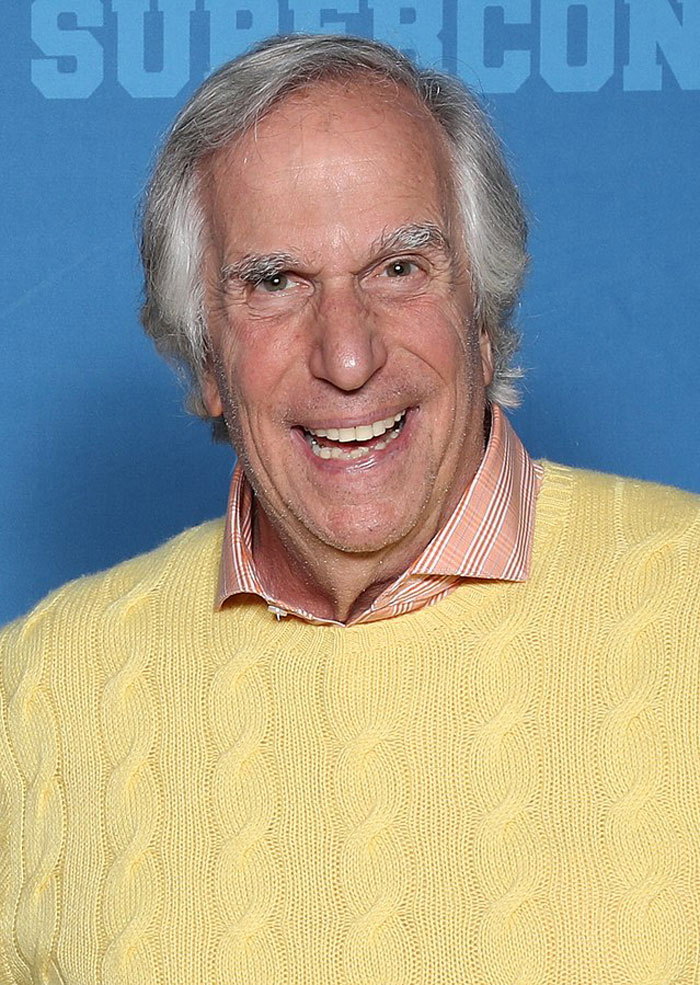 Smiling older male actor in a yellow sweater at a convention, representing actors who revived their career with a role
