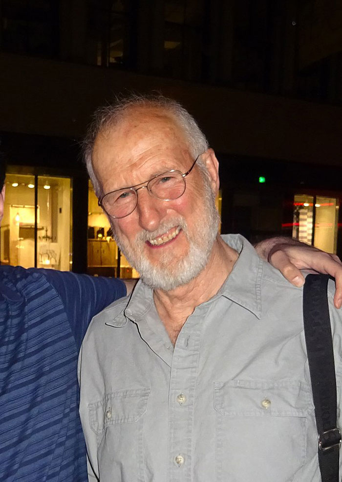 Elderly man with glasses and gray beard smiling outdoors, representing actors who revived their career with a single role.