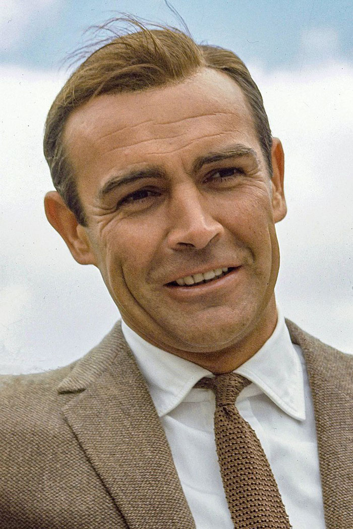 Close-up of a smiling actor wearing a brown suit and tie, symbolizing actors who revived their career with a single role.
