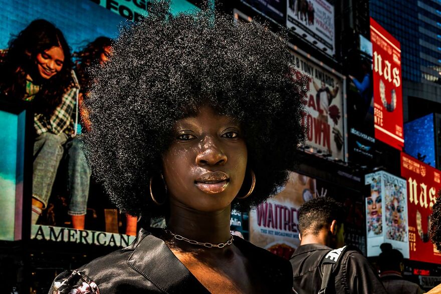 Portrait of a beautiful woman with natural afro hairstyle captured by photographers around the world in a vibrant cityscape.