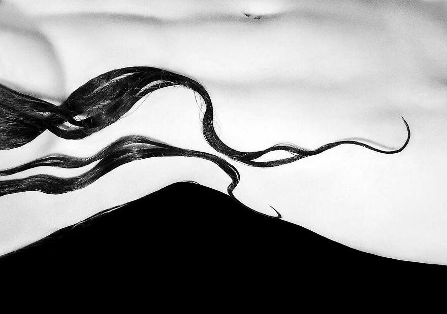 Abstract black and white image of flowing hair strands resembling waves, showcasing artistic photography of beautiful women.