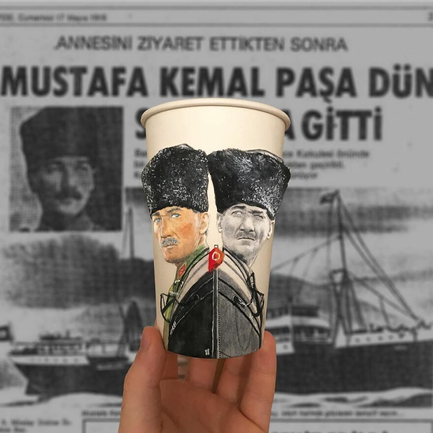 Hand holding a paper cup with detailed illustrations of historical figures, showcasing art on paper cups while traveling.