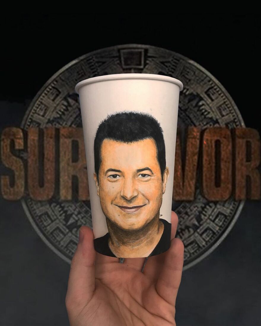 Hand holding a paper cup with a detailed portrait illustration as part of artist’s travel-themed paper cup drawings.