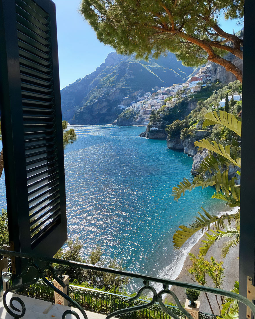 Beautiful coastal scenery with blue sea and hillside village viewed through an open window.