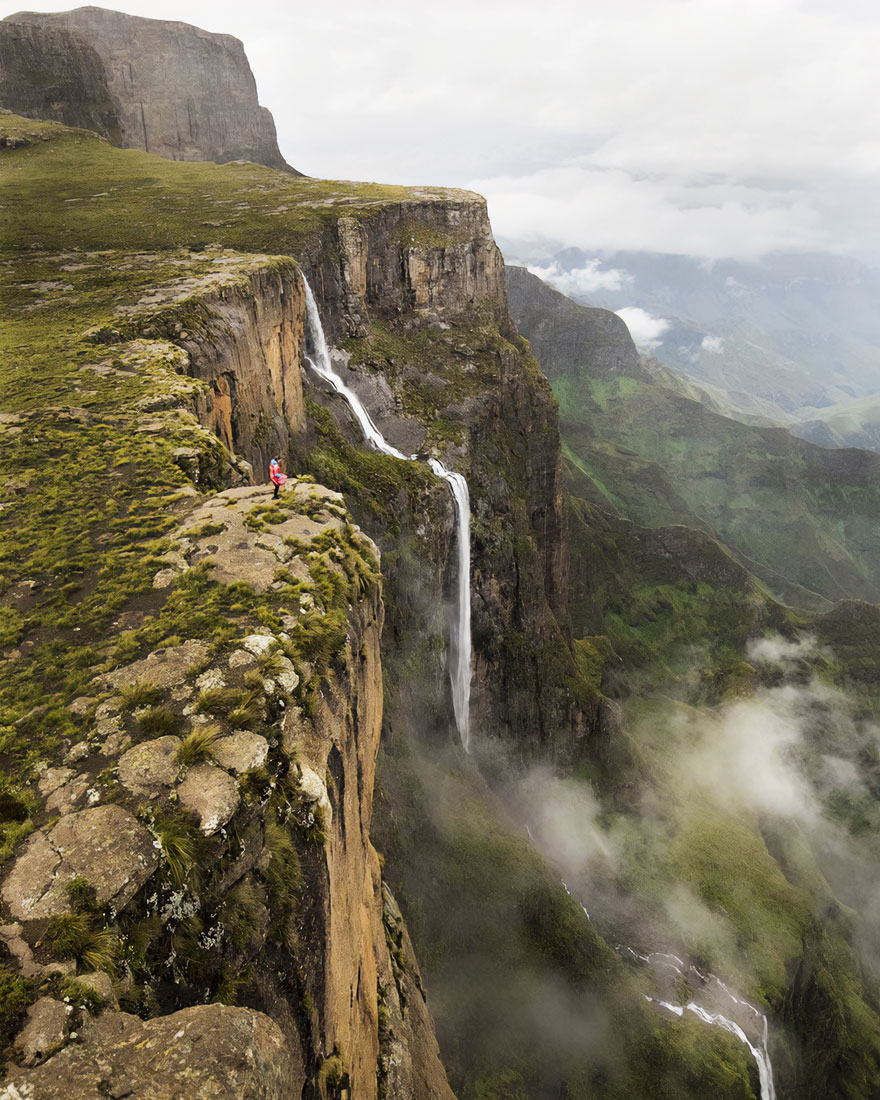 Breathtaking view of a hiker on a cliff with a waterfall in the background, capturing the beautiful scenery.