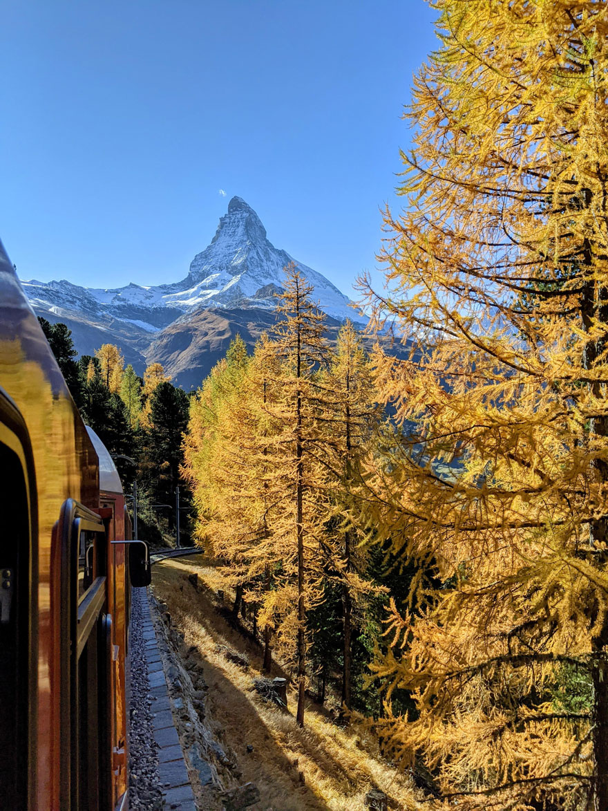 Train passes autumn trees with the Matterhorn in the background, capturing beautiful scenery.