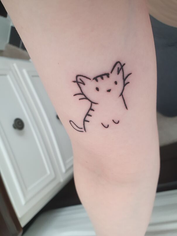 Minimalist cat tattoo on forearm, showcasing impressive new tattoos.