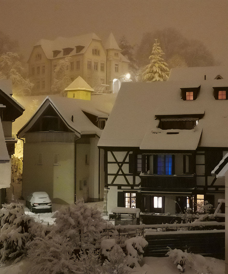 Snow-covered village at night, with charming houses and a beautiful scenic backdrop.