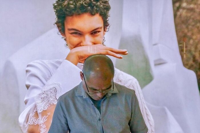 Man posing with an optical illusion photo where a woman appears to cover his head, a lucky accident captured by photographer Edas Wong.