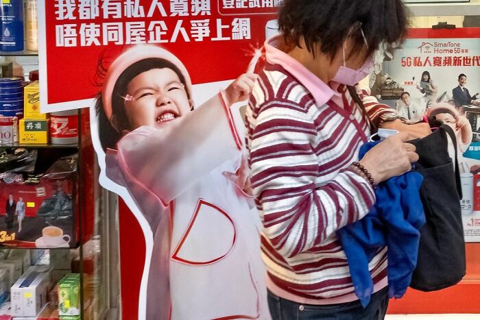 Woman in striped sweater with mask holding clothes next to a playful lucky accident photo of a smiling child by Edas Wong