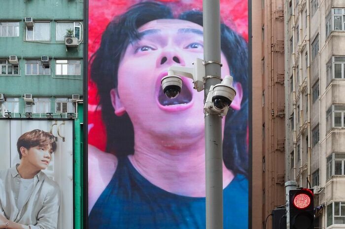 Surveillance cameras aligned with a giant digital screen showing a man’s open mouth, a lucky accident captured by photography.