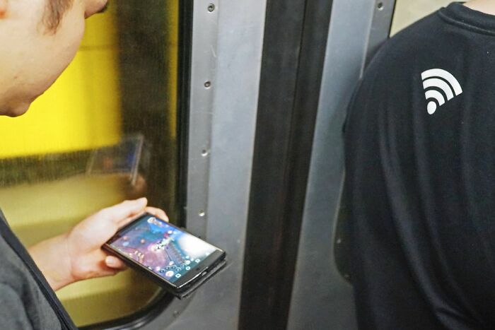 Person playing a mobile game near a door with a WiFi symbol on a black shirt in a candid lucky accident photo.