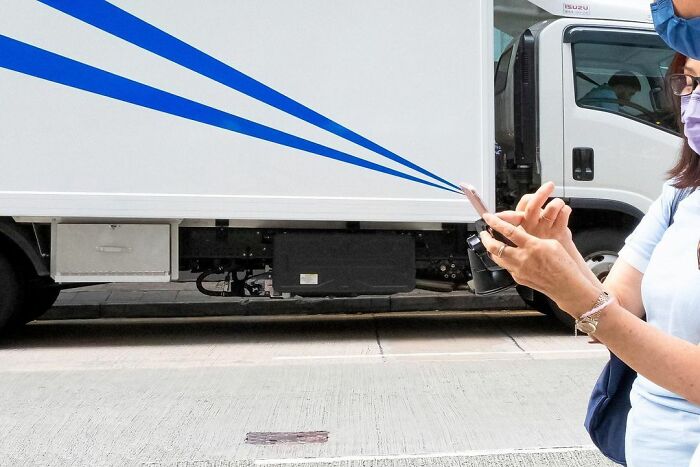 Woman holding a camera on a street with a truck in the background, illustrating lucky accidents captured by photographer.