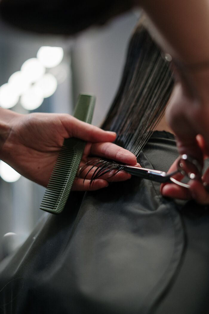 Close-up of hair being cut with scissors and comb, illustrating behind the scenes of reality TV transformations.