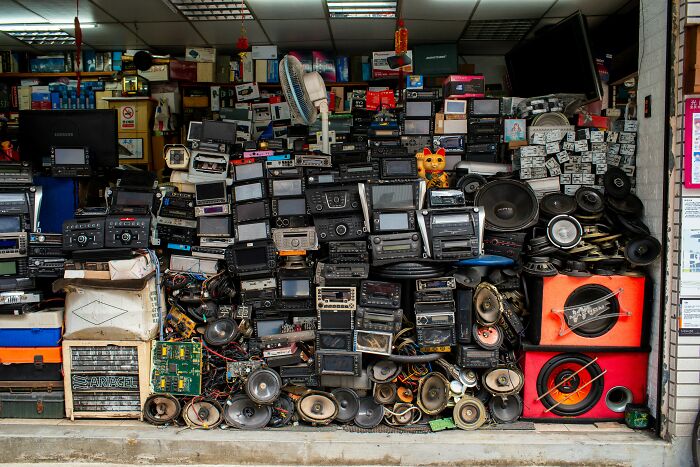 Stack of vintage electronics and audio equipment in a cluttered shop reflecting reality TV's fake and staged environments.