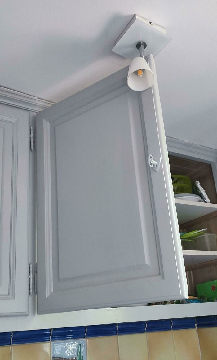 Awful interior design showing a kitchen cabinet blocking a ceiling light fixture.