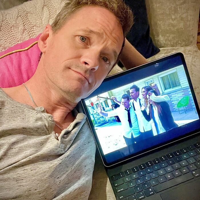 Man lying on couch watching a laptop screen showing a group of actors, highlighting career revival with a single role.