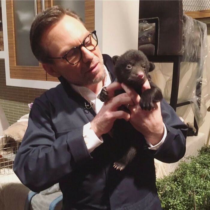 Man wearing glasses holding a small bear cub indoors, related to actors who revived their career with a single role.