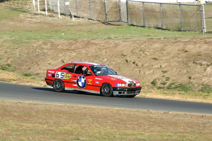 Red race car with BMW logo speeding on a track during an outdoor racing event, highlighting conspiracies proven real.