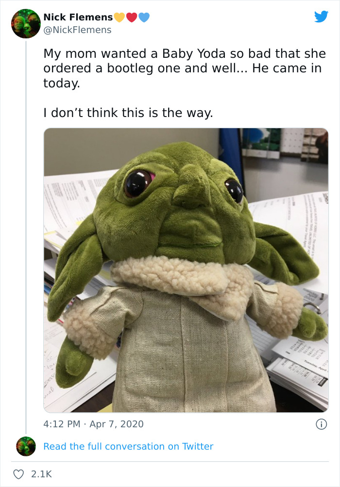 Creepy plush toy resembling Baby Yoda with unsettling large eyes and distorted features on a cluttered desk.