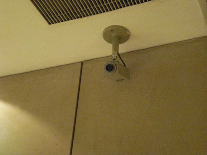 Surveillance camera mounted on ceiling in a beige indoor space, illustrating conspiracies that were proven real.
