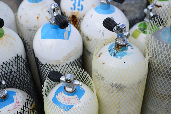 Several white and blue scuba diving tanks grouped together, used by deep sea divers for underwater exploration.