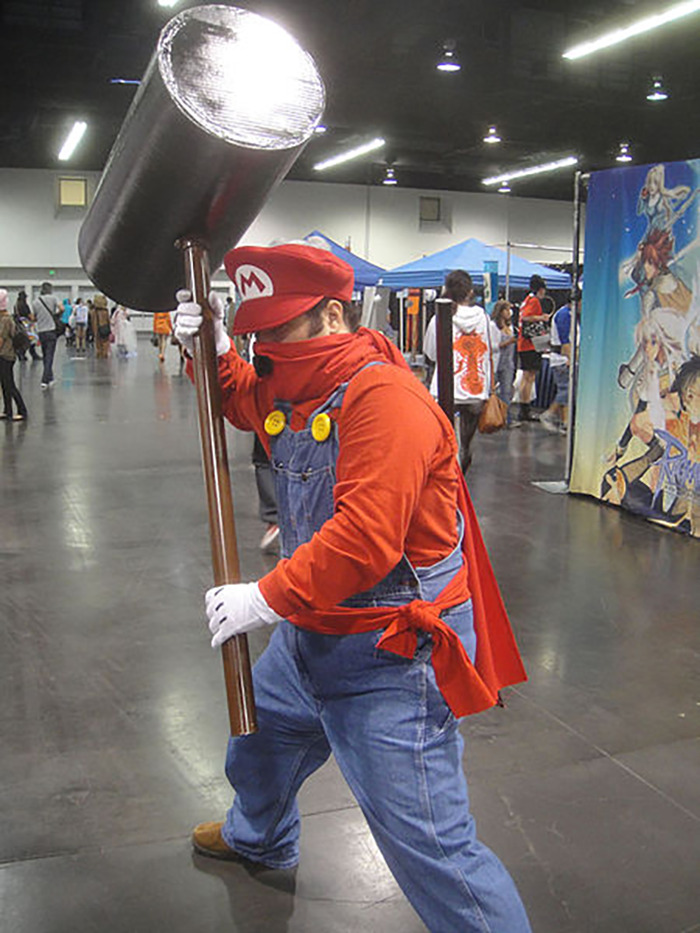 Cosplayer dressed as Mario holding oversized hammer at convention, relating to conspiracies that were proven real online.