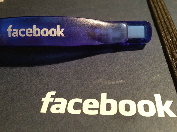 Blue Facebook-branded pen resting on a dark surface with Facebook logo, illustrating conspiracies proven to be real online.