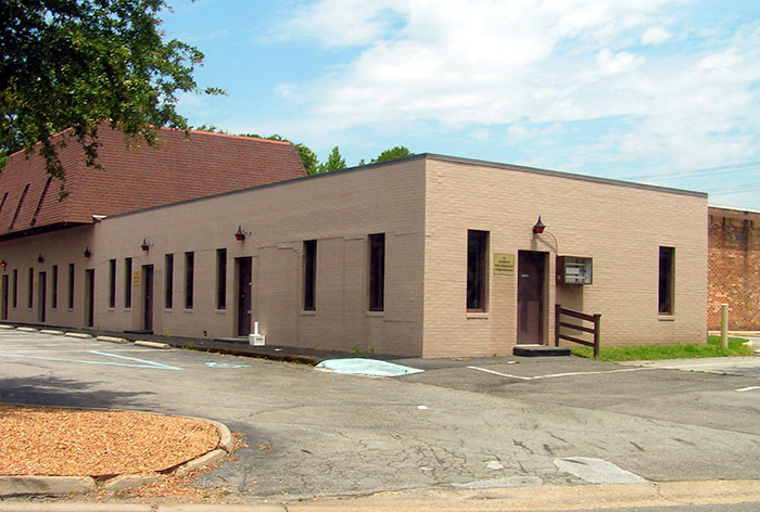 Beige brick building with multiple windows and a parking lot, representing conspiracies proven to be real.