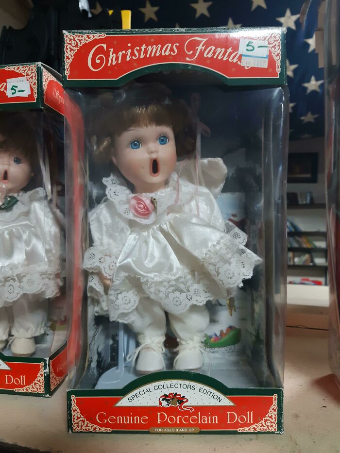 Creepy porcelain doll with wide open mouth and blue eyes in original Christmas Fantasy packaging, eerie toy collectible.