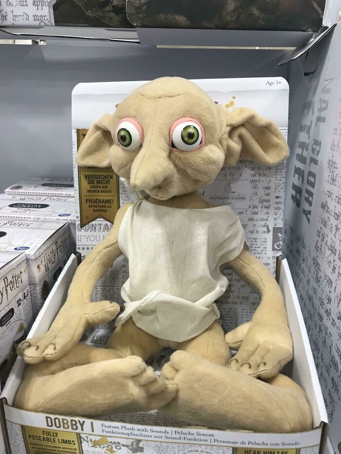 Creepy toy with oversized eyes and long limbs sitting in a box, evoking hilariously creepy toy nightmares.