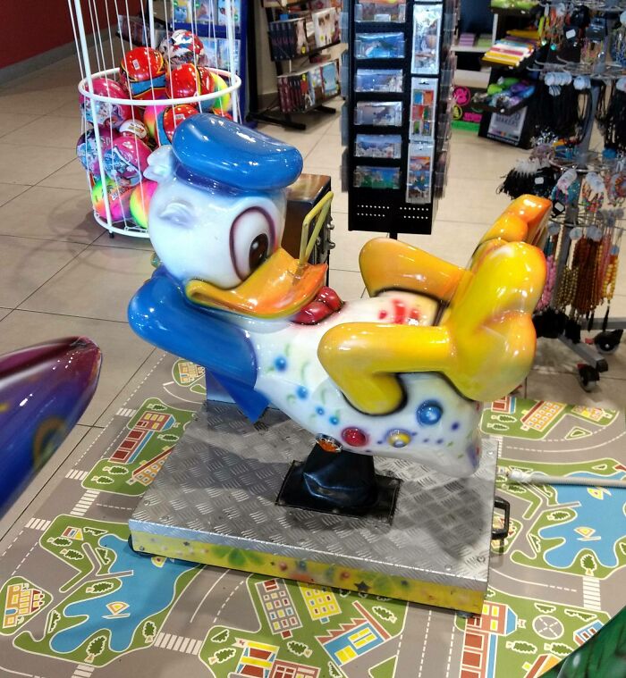 Creepy vintage duck ride-on toy with exaggerated features and bright colors displayed in a store setting.
