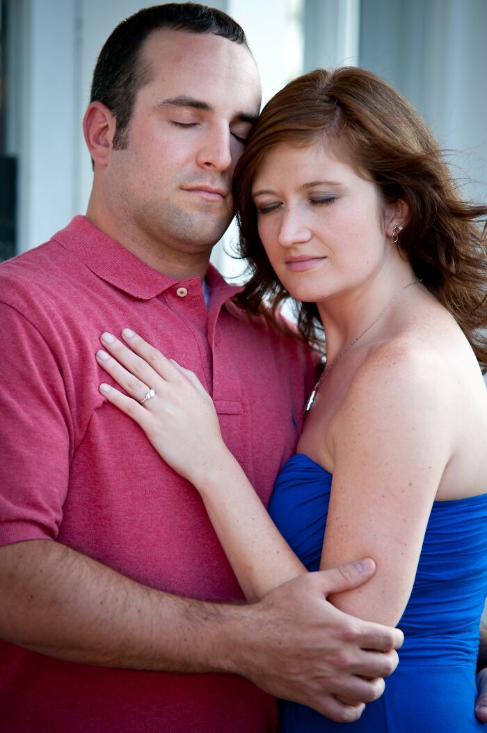 Couple embracing with eyes closed, wearing casual outfits, portraying a humorous romantic moment.