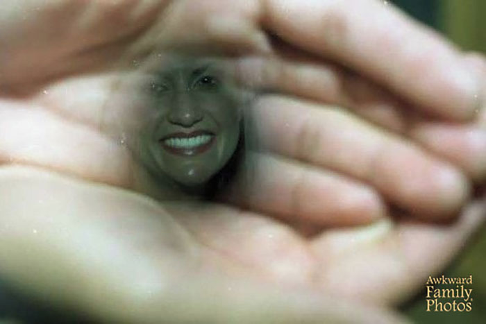 Funny couples' picture through hands forming a lens, showing a smiling woman.