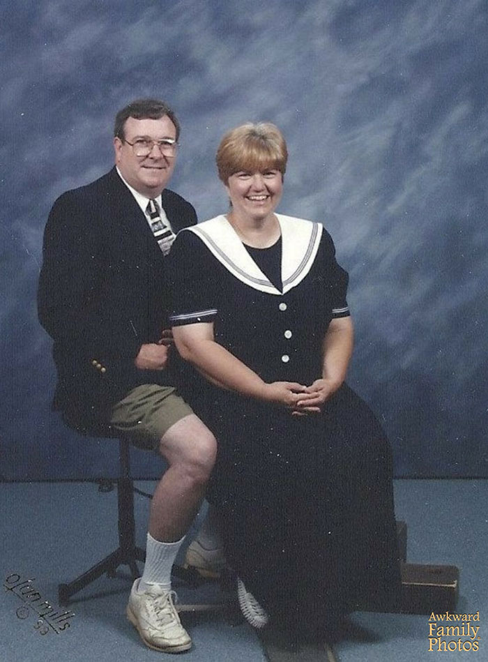 A couple poses humorously in a studio, with the man wearing a suit jacket and shorts, embodying funny couple moments.