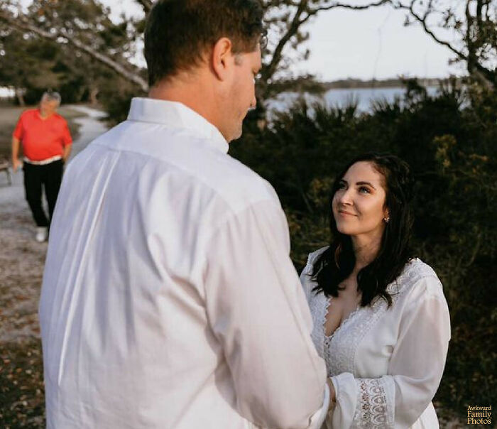 Funny couples picture with a man and woman in white shirts, smiling at each other, with a man in a red shirt approaching.