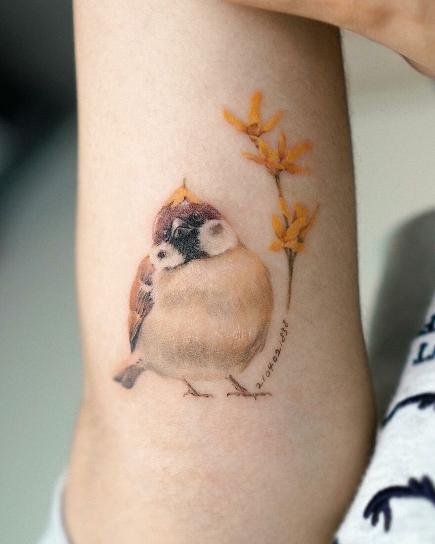 Painting-like tattoo of a realistic sparrow and flowers on forearm.