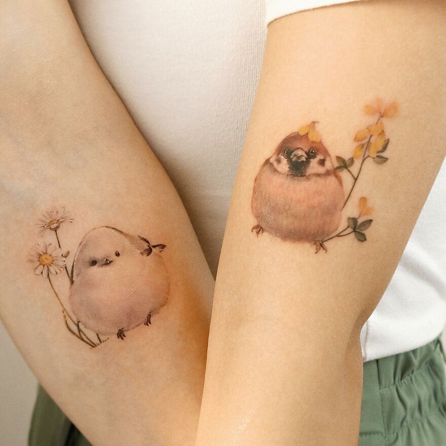 Painting-like tattoos of birds with flowers on arms.