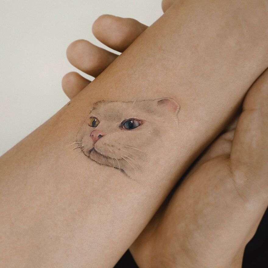 Cat tattoo on forearm, resembling a painting-like art style.