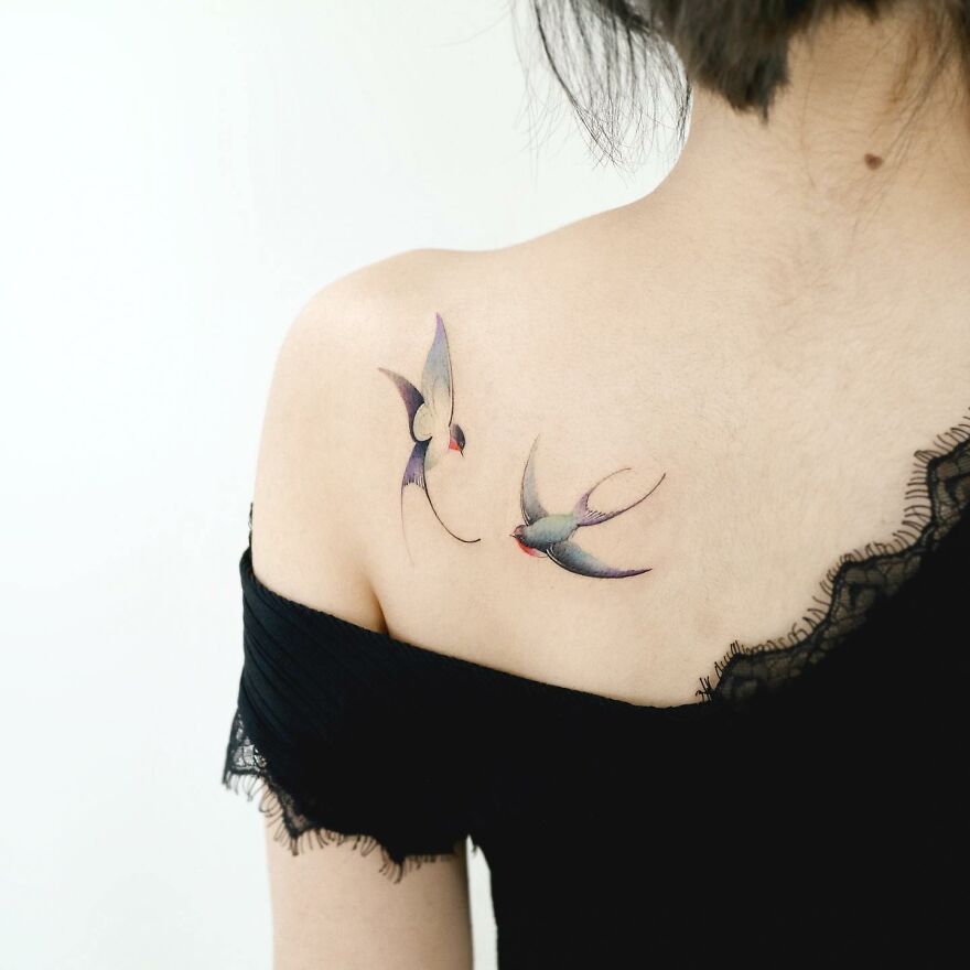 Painting-like tattoos of swallows on a person's shoulder, showcasing intricate artistry.