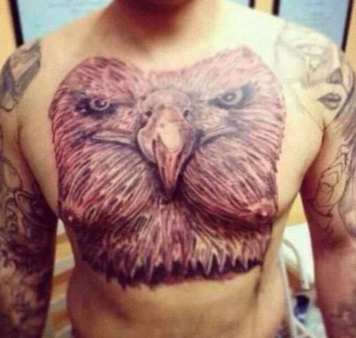 Chest tattoo of an eagle with outstretched wings, surrounded by other tattoos on arms.