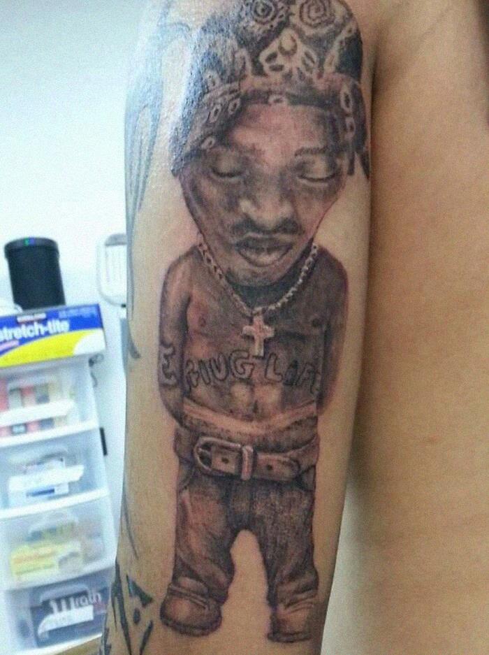 Tattoo of a small figure with exaggerated features wearing a bandana and necklace.