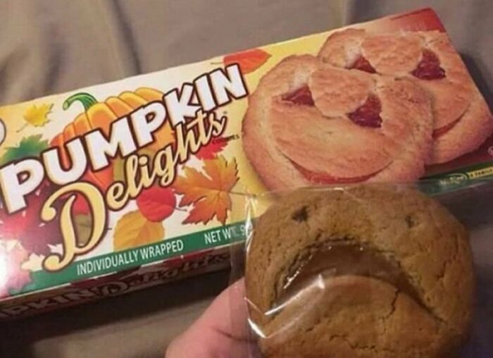 Cursed food: a pumpkin cookie with an unappealing face, contrasting with the cheerful box design.