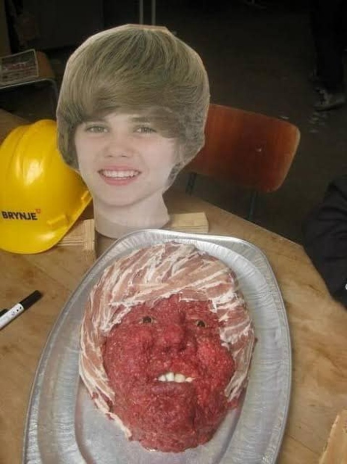 A platter with a cursed food creation resembling a face made of meat, set on a table with a hard hat nearby.