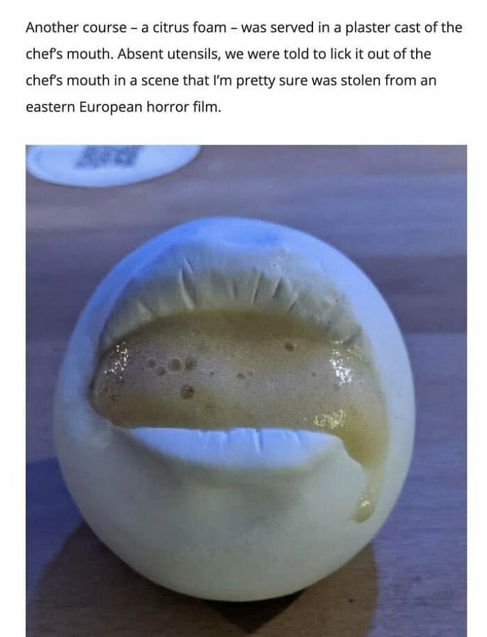 Cursed food: a citrus foam served in a chef’s mouth plaster cast, resembling a horror film scene, without utensils.