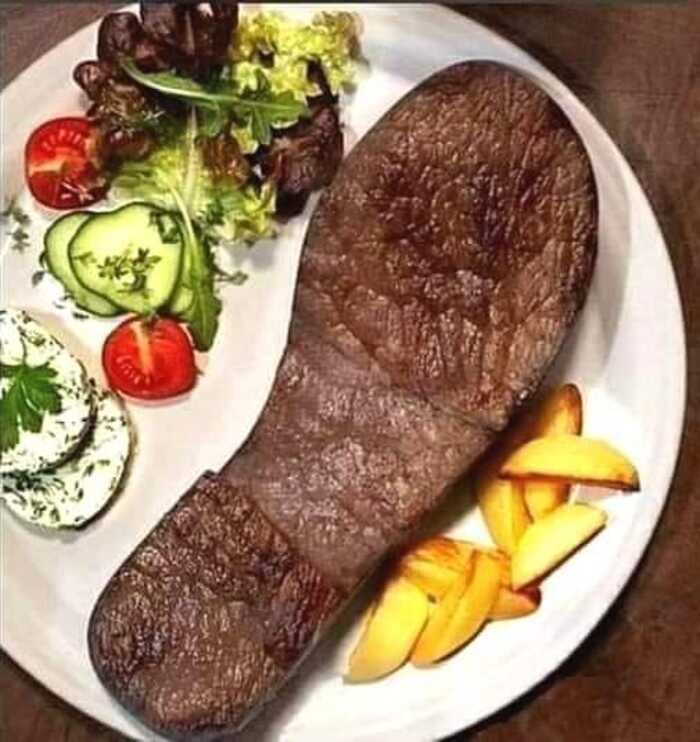 Cursed food resembling a shoe sole on a plate with salad and potato wedges.