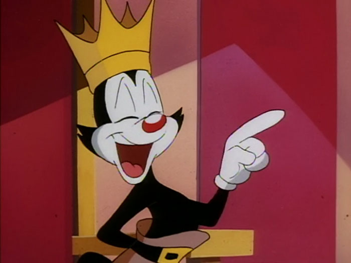 Cute animated character wearing a crown, smiling and pointing playfully.